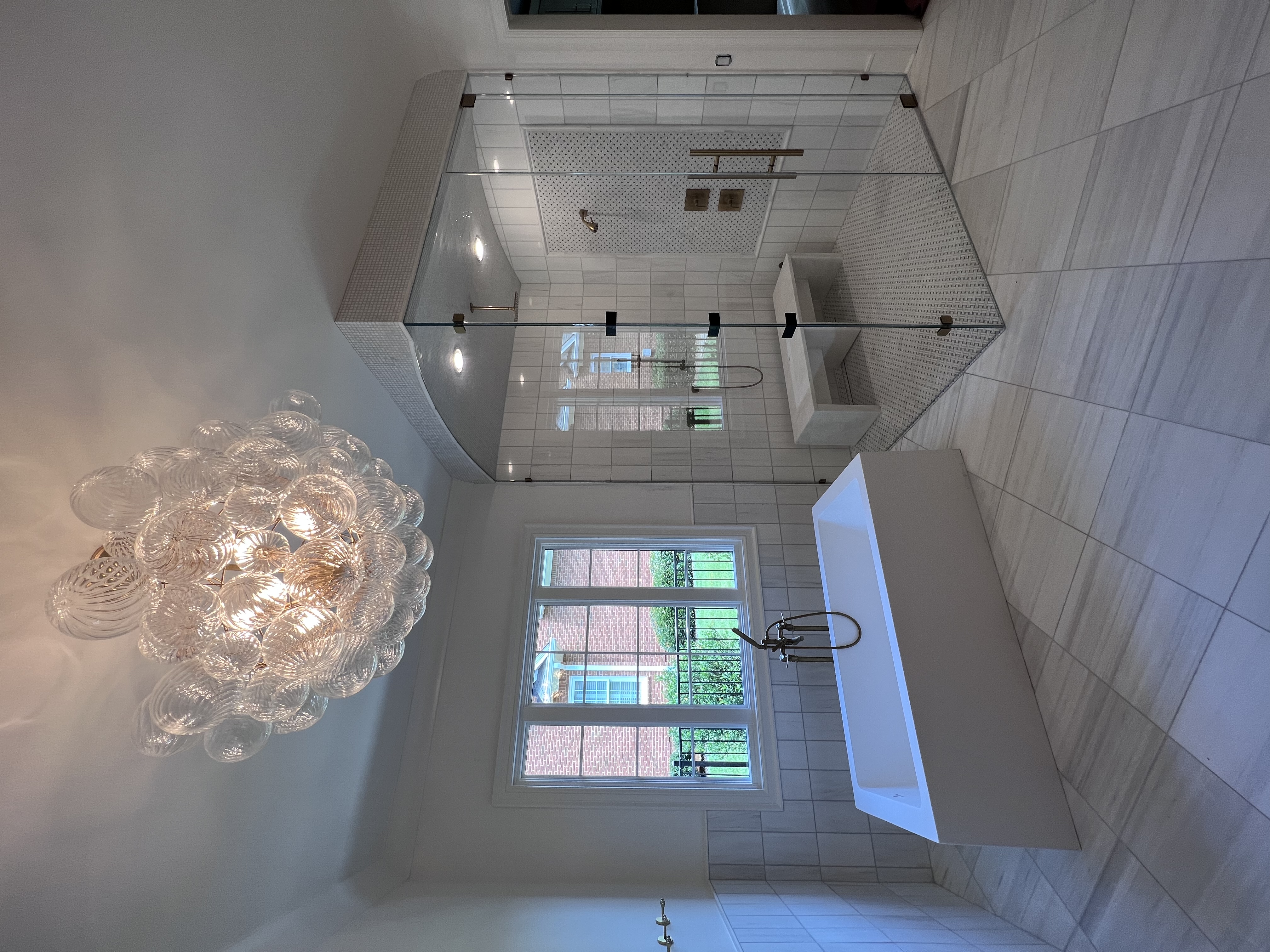 This gorgeous shower includes an arched glass piece with a contemporary ladder style commercial handle and low iron glass!
